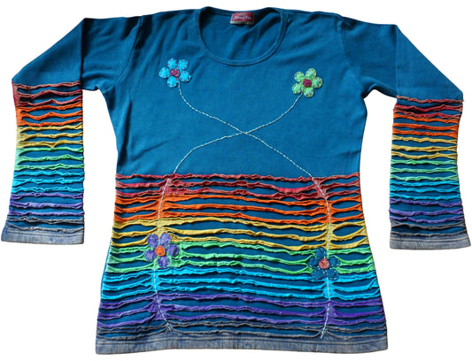 Main image: Cotton jersey long sleeve top in teal with applique flowers, embroidery & rainbow razor cut panels. The razor cut sections are applied to the lower front of the top & sleeves with applique flowers & embroidery to the front. Plain colour to the back of garment. Stretch cotton for comfort & ease of wear.